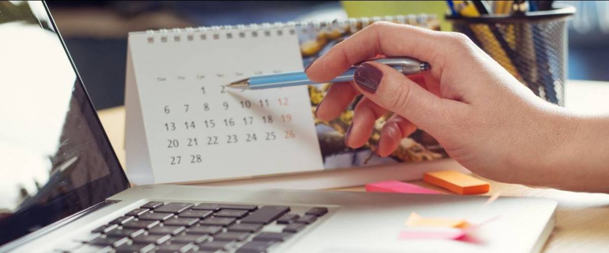 Woman's hand points a pen at a date on a calendar
