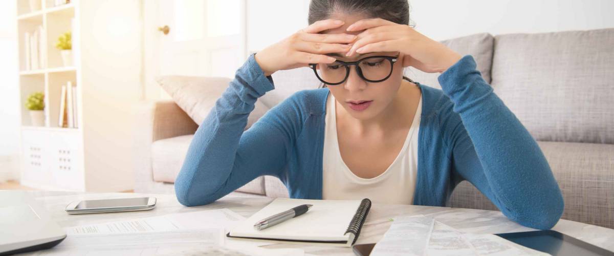 worried young woman is doing banking and administrative work holding bills at home.