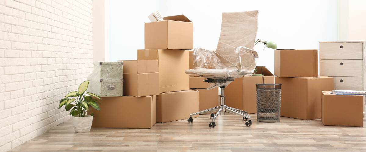 Moving boxes and stuff near white brick wall in room