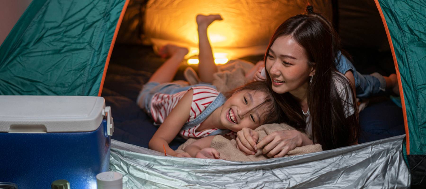 Asian woman playing and staying in tent with her daughter and having fun with camping tent in their bedroom a staycation lifestyle