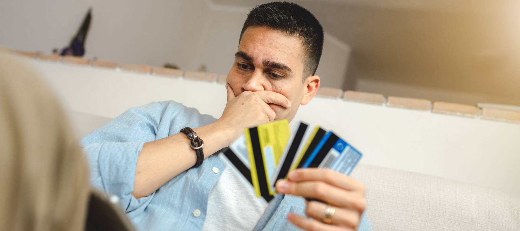 Man holding four credit cards looking at his computer