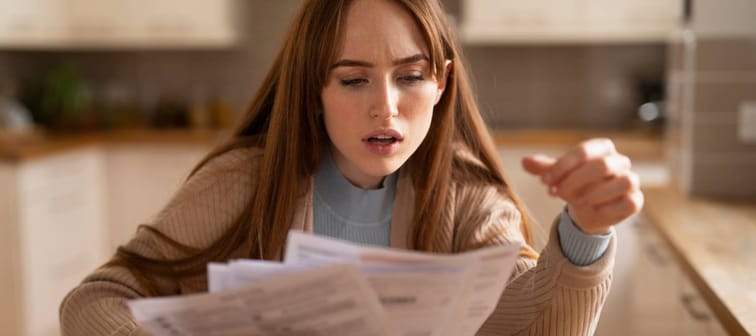 Young woman shocked while reviewing bills