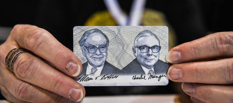 A woman holds a card with images of Warren Buffett (L) and Charlie Munger (R), April 29, 2022.