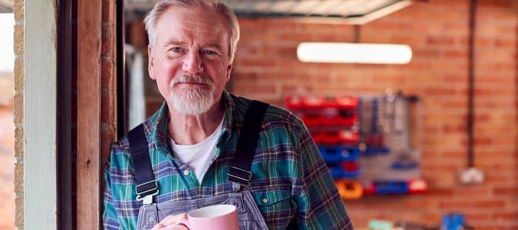 A man in overalls working in a garage.