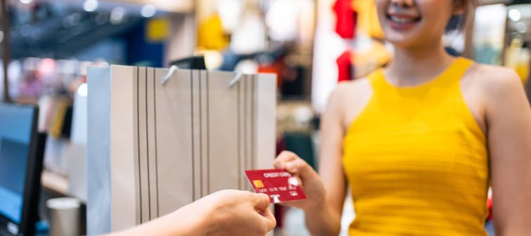 Young Asian woman in yellow shirt paying by credit card