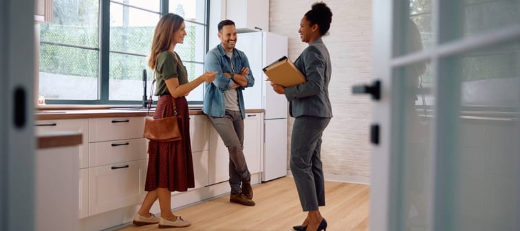 Young couple talks to a Realtor inside the kitchen of an open house