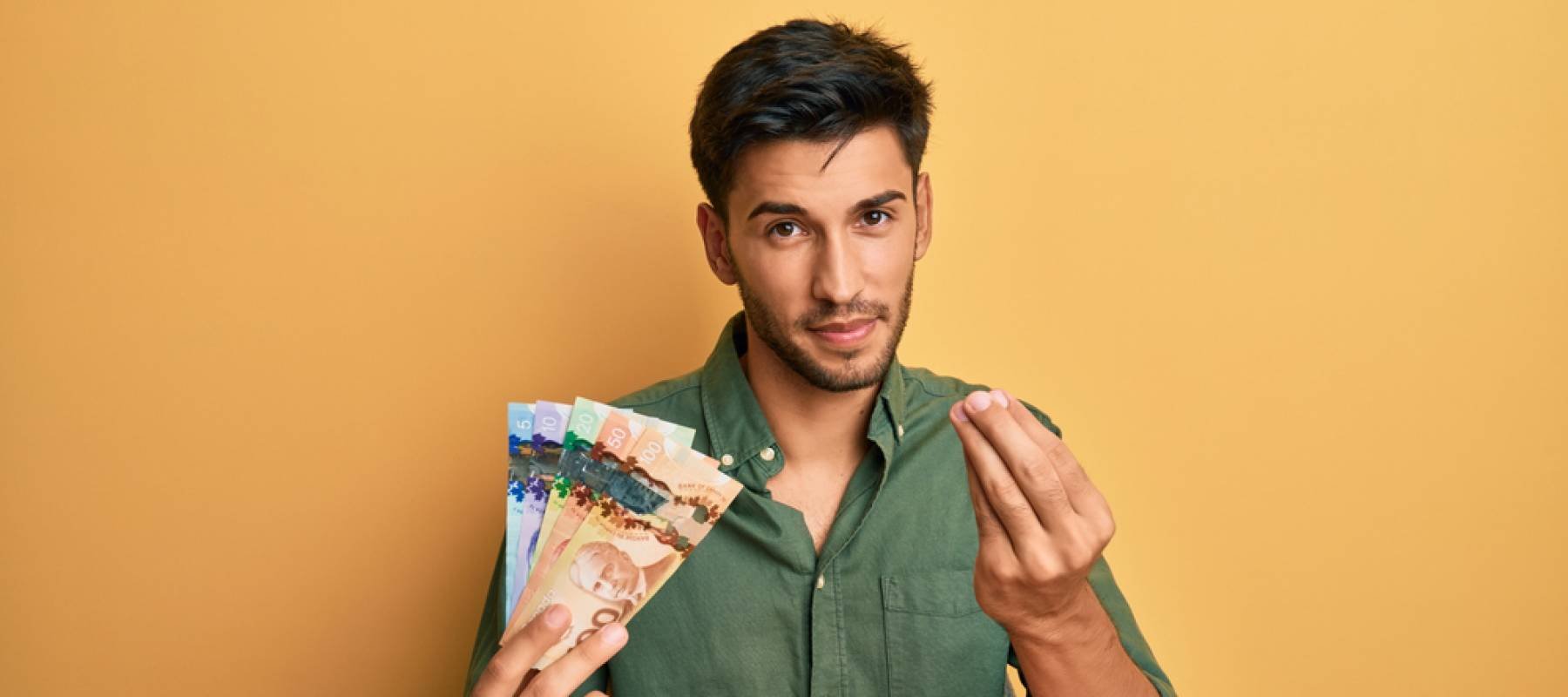 Young handsome man holding canadian dollars