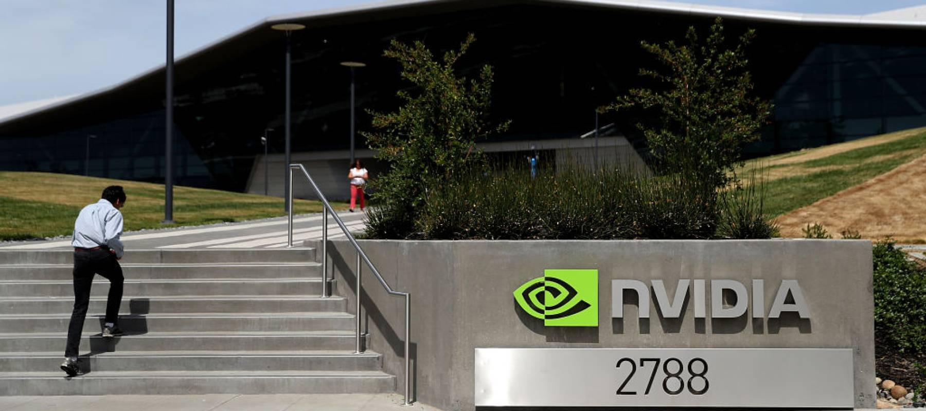 sign is posted in front of the Nvidia headquarters as employees walk up a set of stairs.