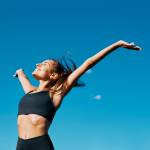 Young woman in fitness clothes smiling outside