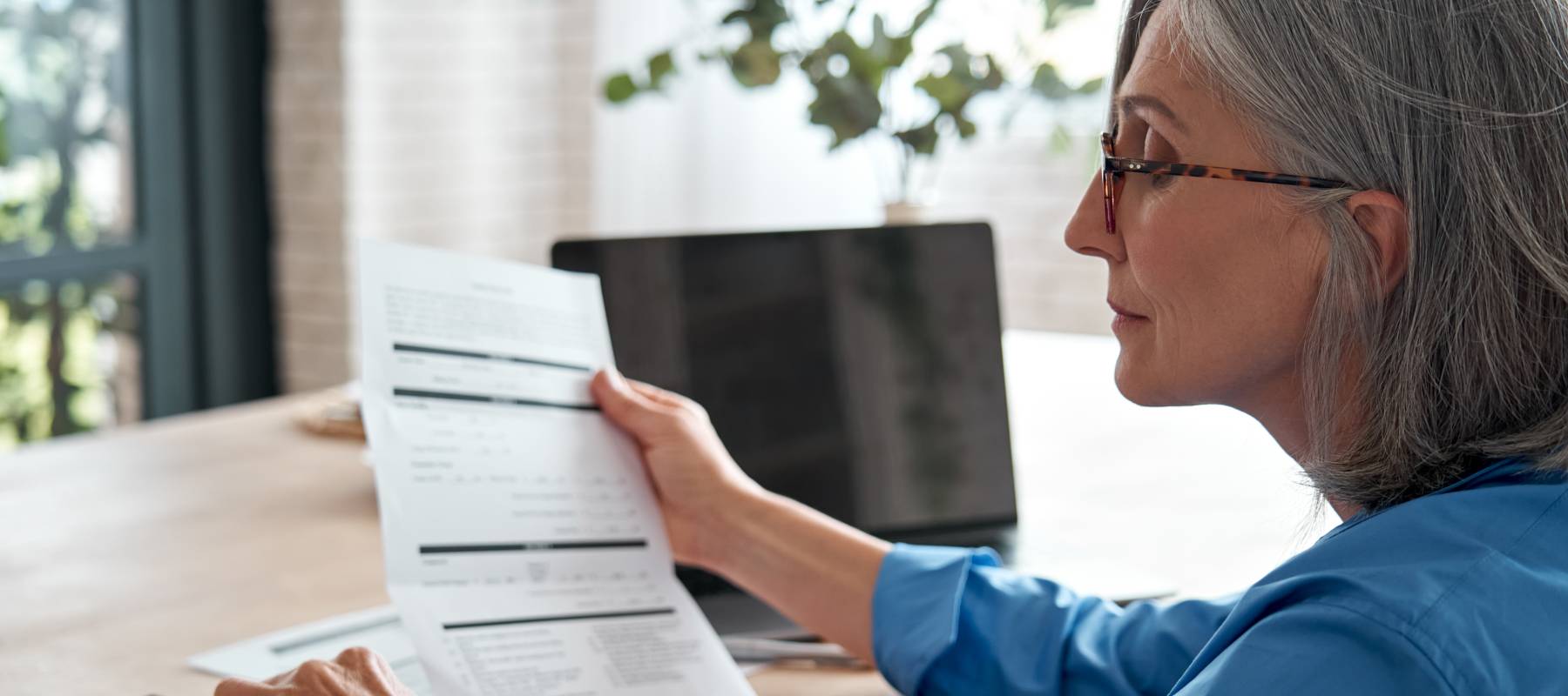 Mature woman reviewing expenses and using a calculator to cut costs