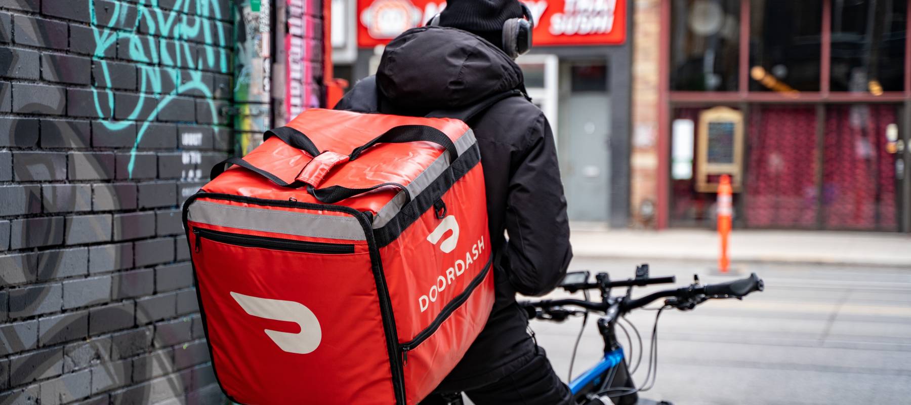 A DoorDash food delivery courier on an bicycle. Toronto, Canada - May 25, 2024