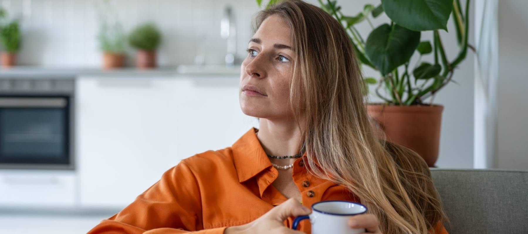 Thoughtful middle aged woman sits on sofa