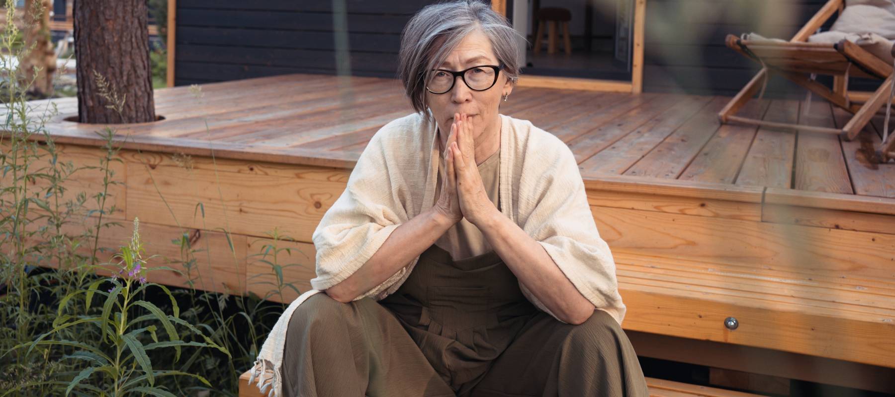 Woman sitting outside on a porch, thinking.