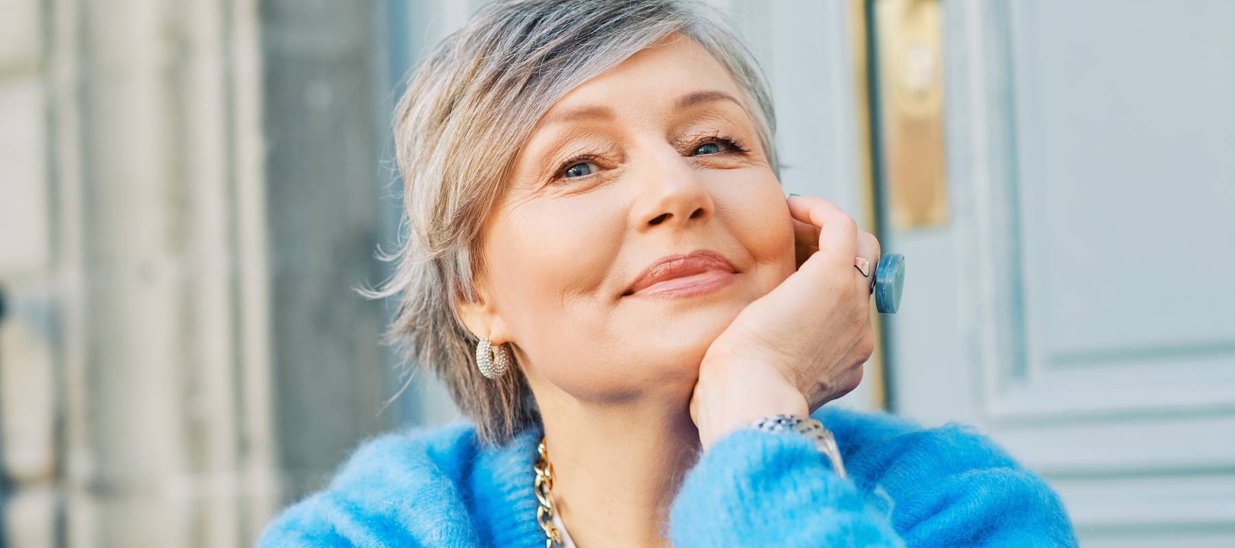Older woman smiling, wearing a blue sweater