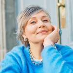Older woman smiling, wearing a blue sweater