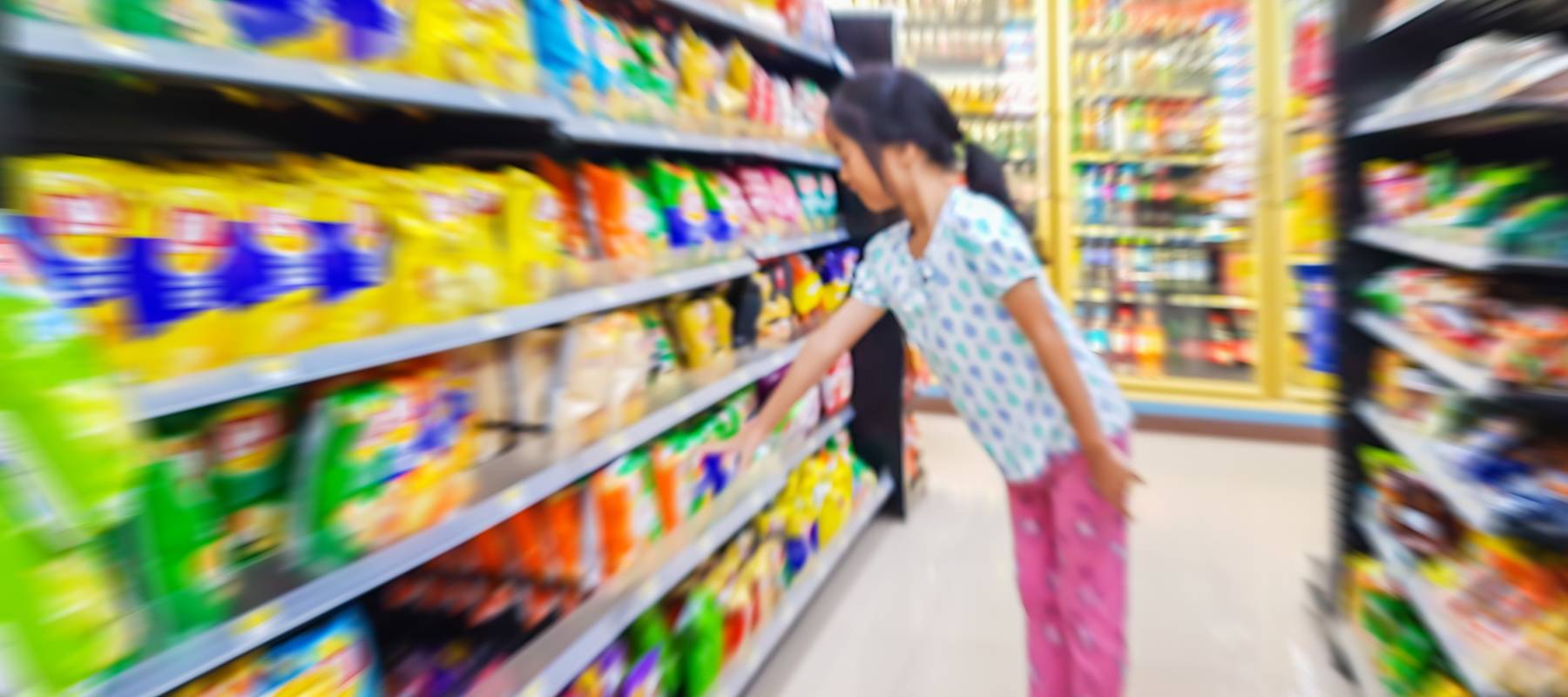 Blur image of Asian kid choose to buy snacks in grocery store