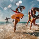 Group of friends are having fun and running to sea beach with inflatable donuts