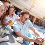 Cheerful group of friends having fun in cafe, taking selfie.