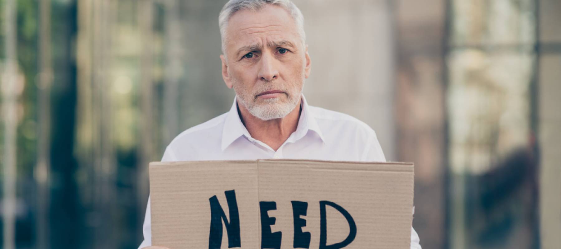 Older man holds up "Need a job" sign