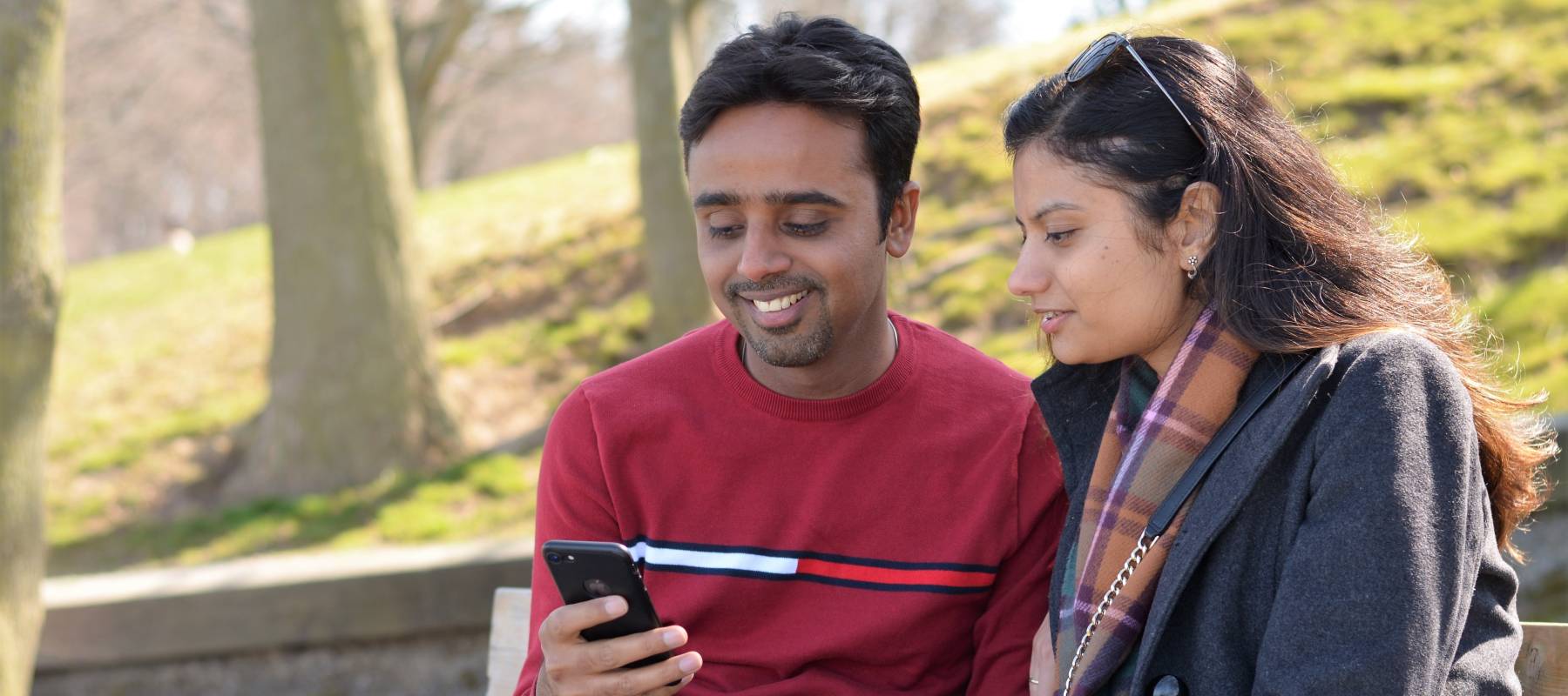 Toronto, Ontario, Canada - April 05, 2021, Cheerful lovely Indian immigrant newcomer couple, at park sitting on bench