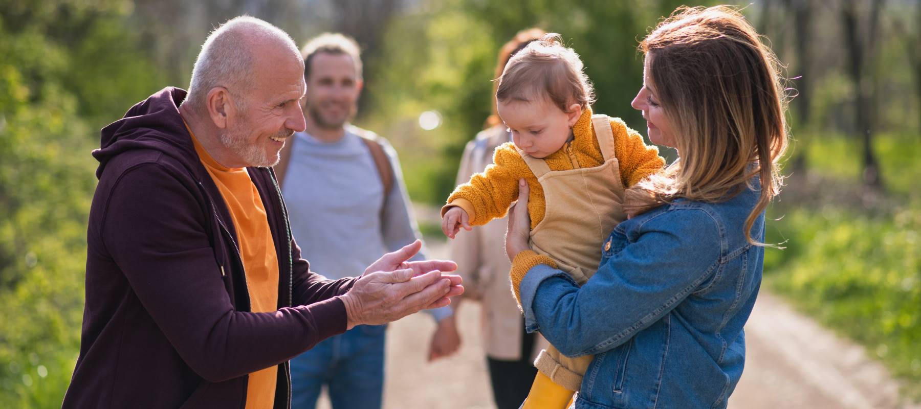 Grandpa talking to baby in mom's arms