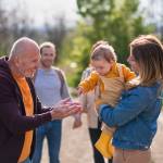 Grandpa talking to baby in mom's arms