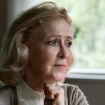 An older woman ponders by a window.