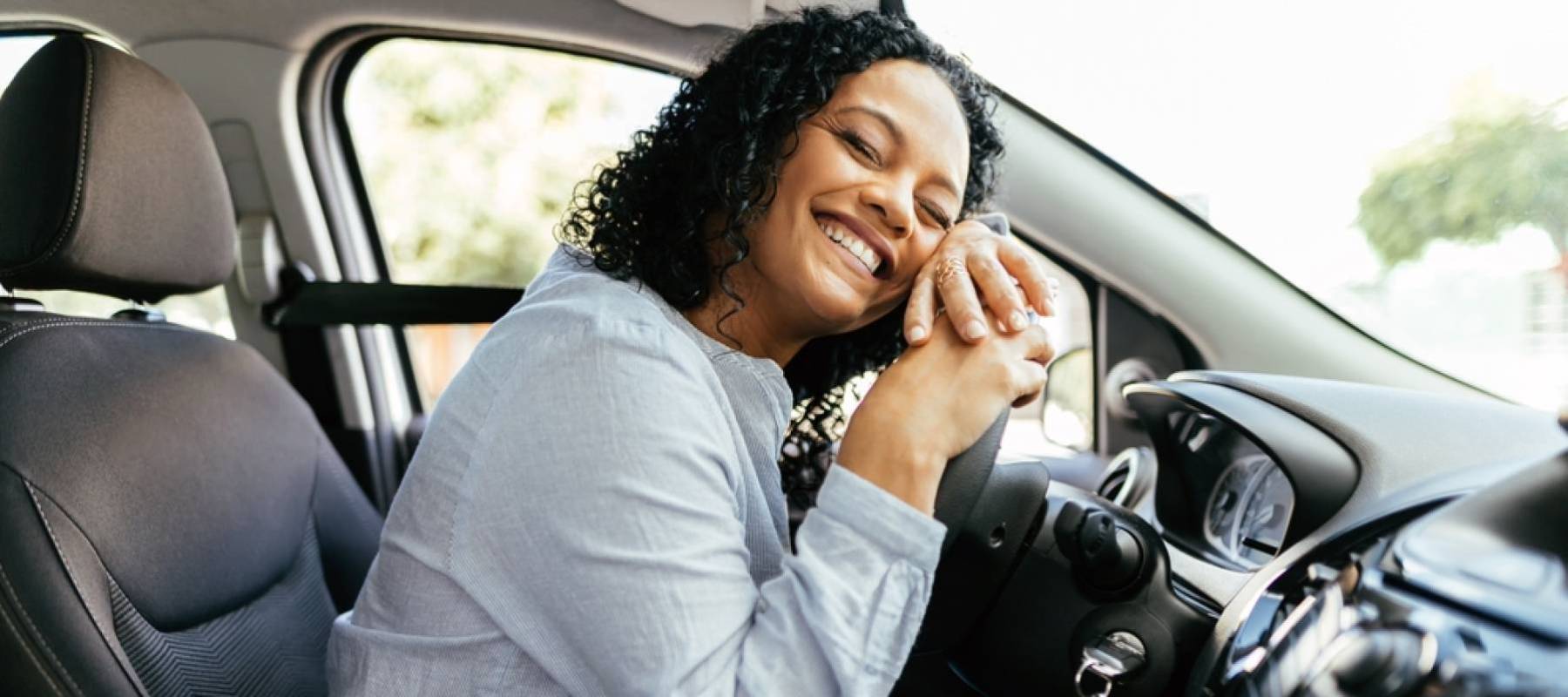 Woman smiling while leaning on steering wheel