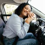 Woman smiling while leaning on steering wheel