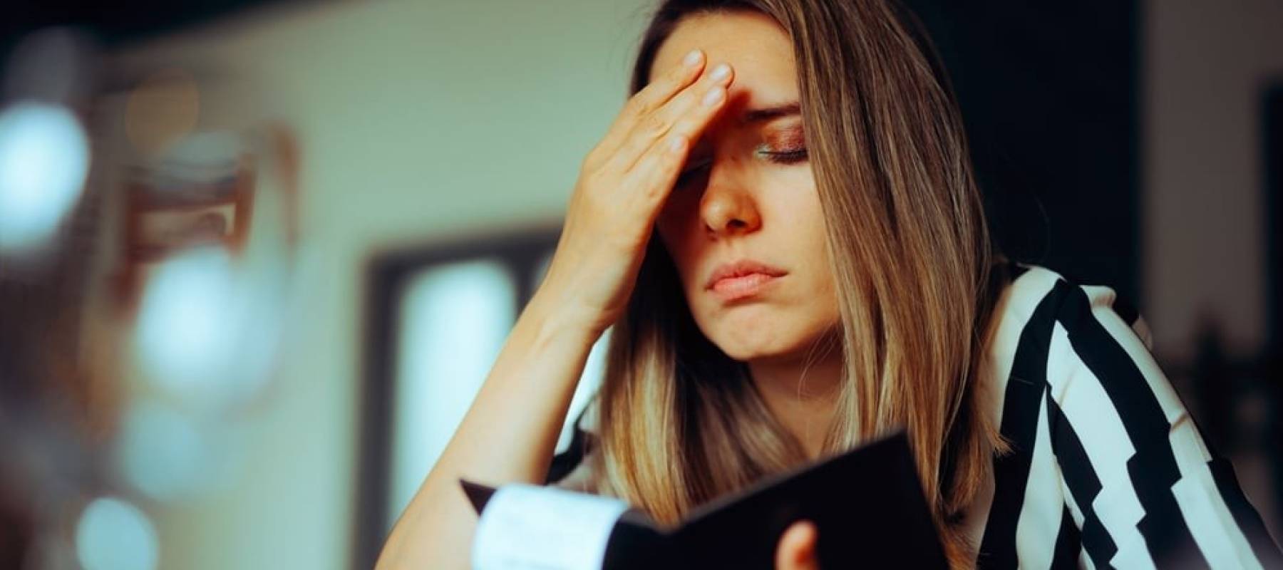 Unhappy young Caucasian woman looking at her check book