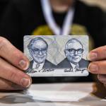 A woman holds a card with images of Warren Buffett (L) and Charlie Munger (R), April 29, 2022.