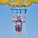 Woman with gray hair with a big smile and a fearless expression parasailing.