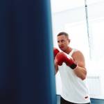 middle-aged boxer training in a gym, fighting with punching bag close up
