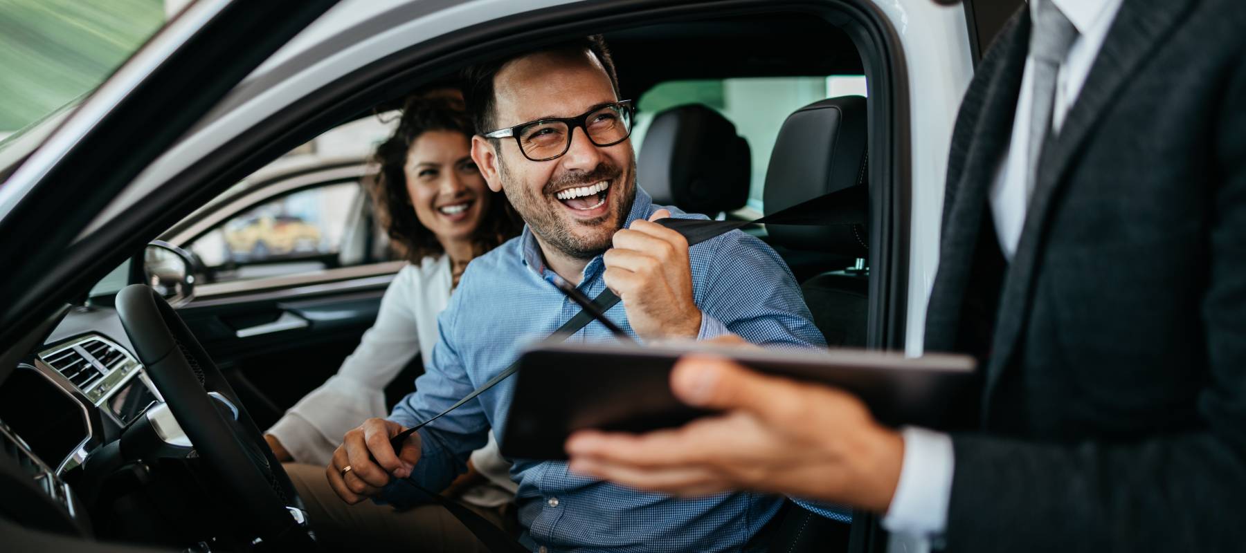 Middle age couple choosing and buying car at car showroom. Car salesman helps them to make right decision.