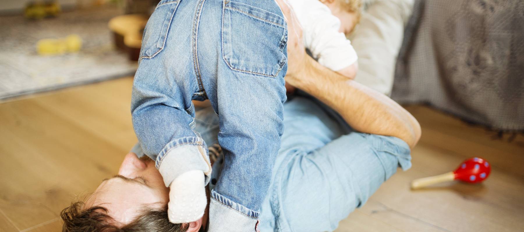 Young father at home playing with his little son.