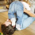 Young father at home playing with his little son.