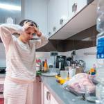 Overwhelmed woman stands in a messy kitchen