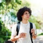 man on campus with coffee, backpack and glasses on morning commute to college