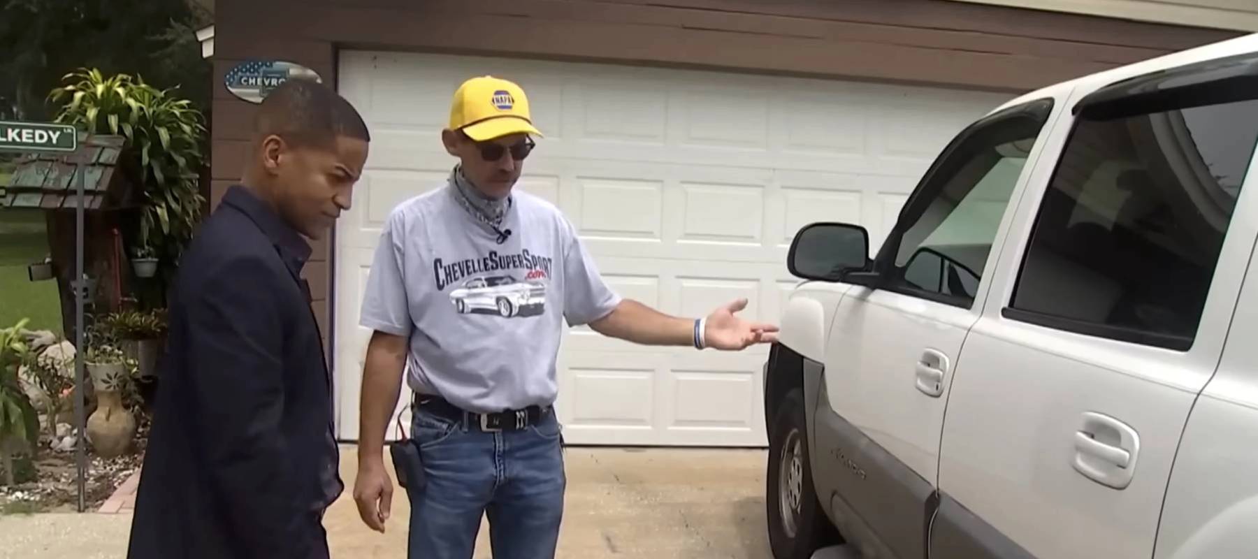 Man and news anchor in front of car