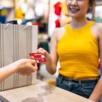 Young Asian woman in yellow shirt paying by credit card