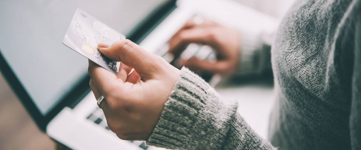 Hands holding plastic credit card and using laptop
