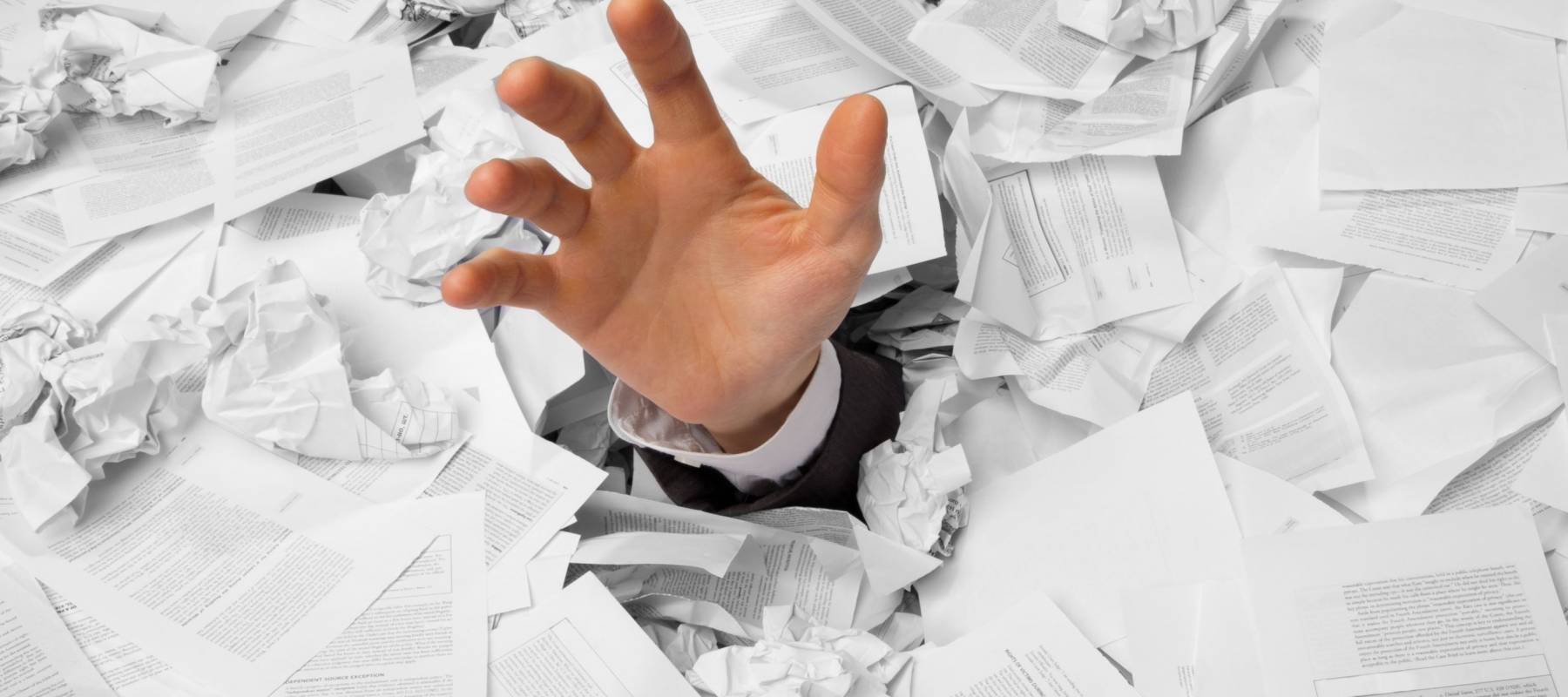 Hand reaches out from big heap of crumpled papers