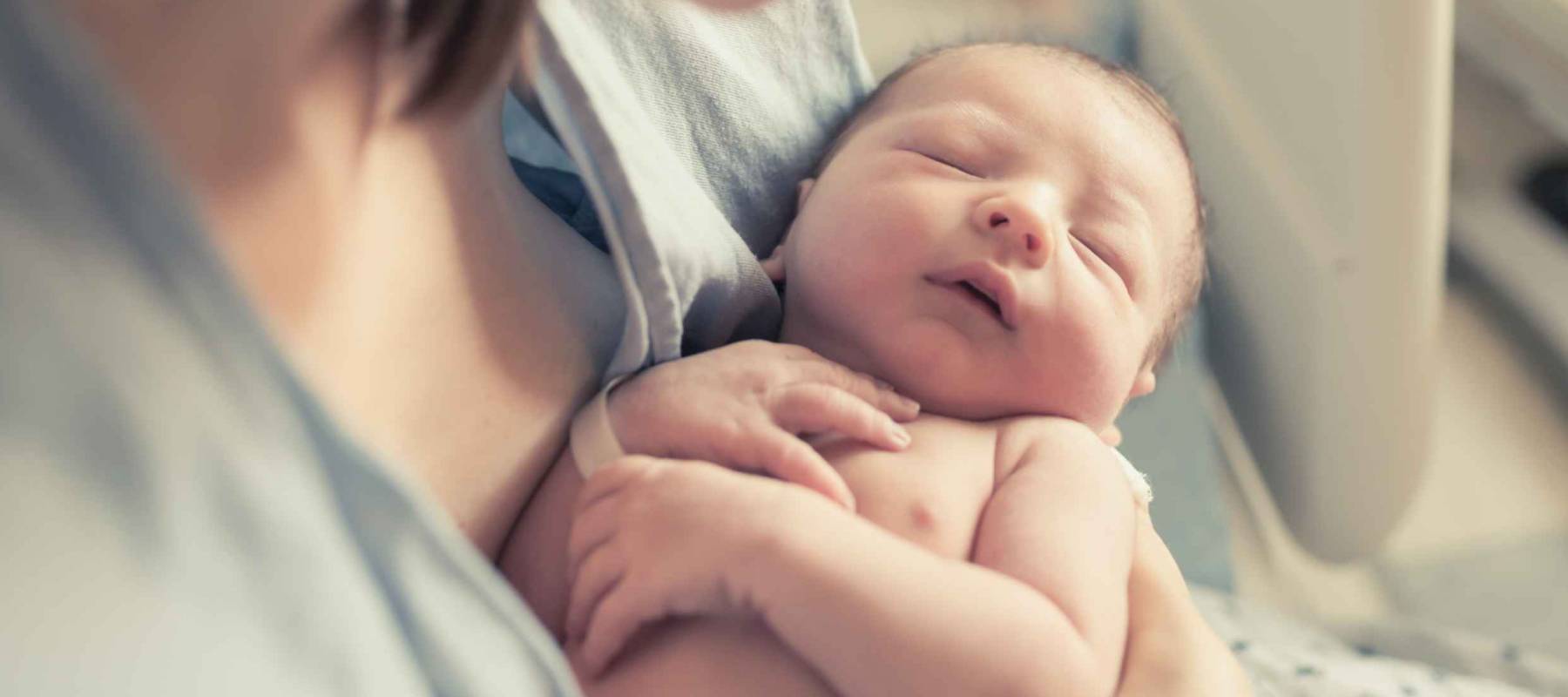 New born baby boy resting in mothers arms.