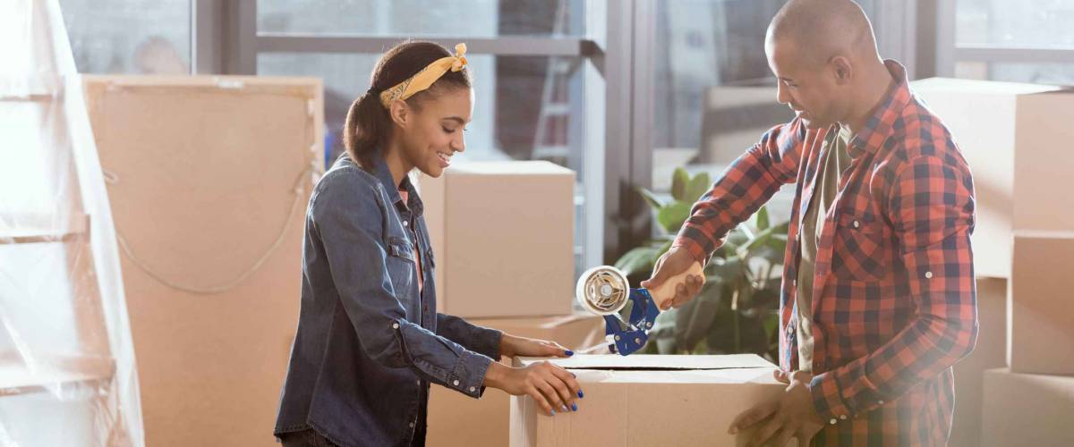 african american couple packing cardboard box to move in new apartment