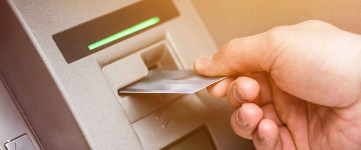 Hand of a man with a credit card, using an ATM. Man using an atm machine with his credit card.