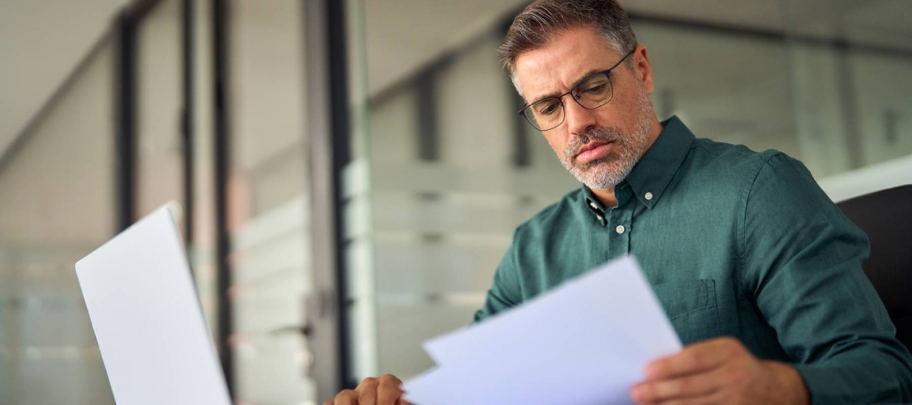 Man looking at papers and laptop