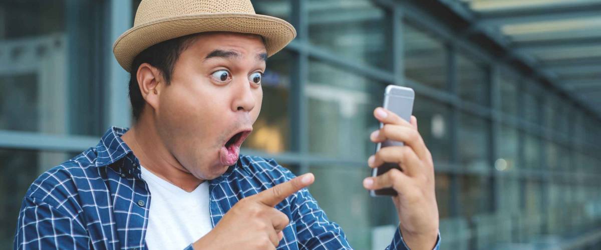 Asian man looking smartphone and shocked