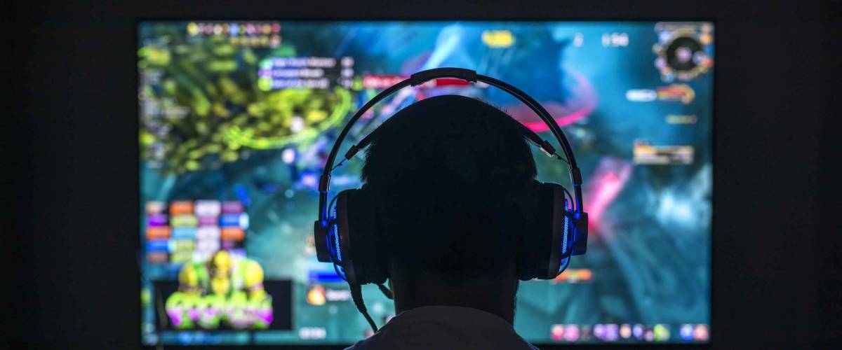 Young gamer playing video game wearing headphone.