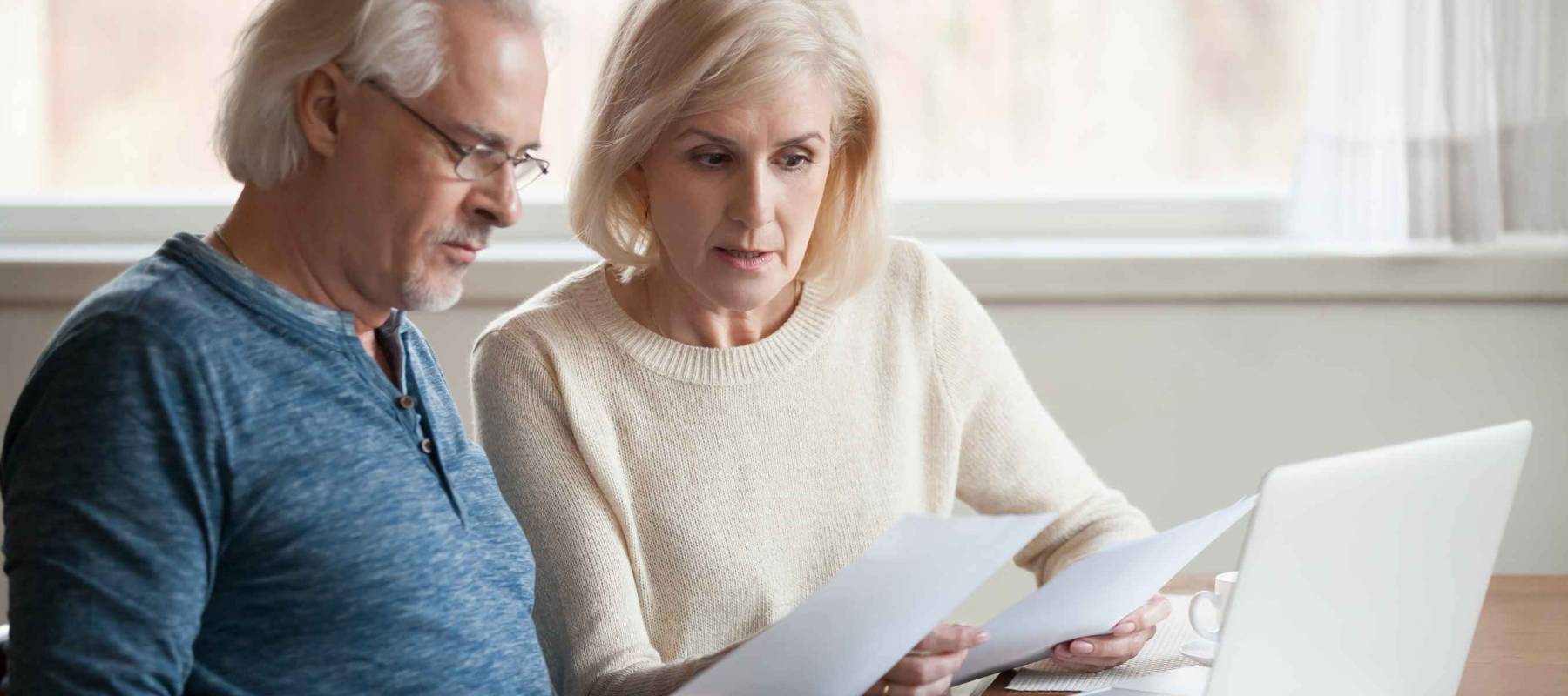 Serious, worried senior couple calculating bills to pay.