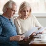 Serious, worried senior couple calculating bills to pay.